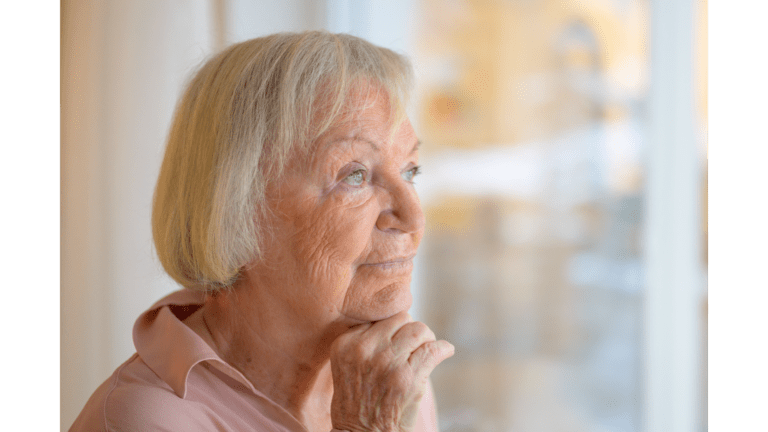 Grand mère qui regarde par la fenêtre d'un air pensif