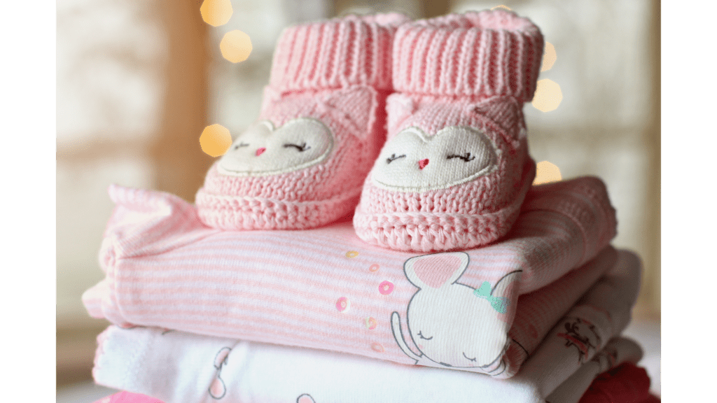 chaussons pour bébé roses sur une pile de vêtements pour bébé